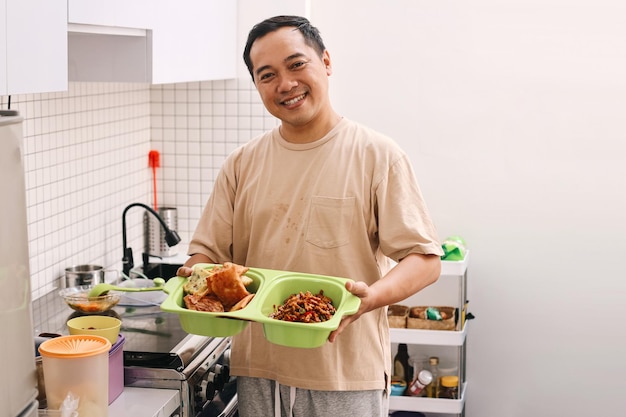 Portrait of Asian man serving food for lunch in the home kitchen