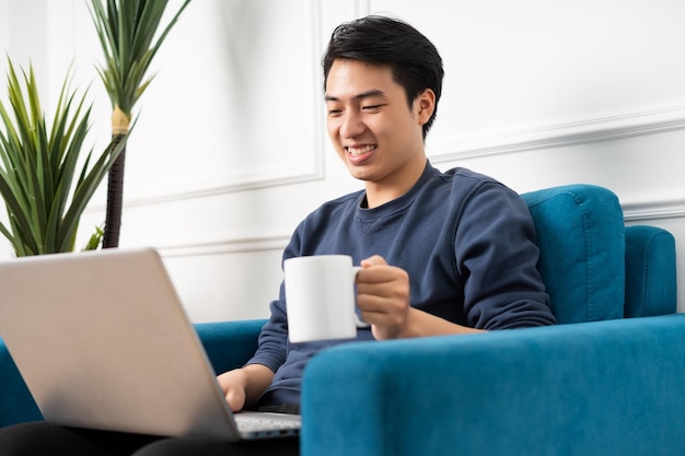 Portrait of asian man sitting on sofa at home