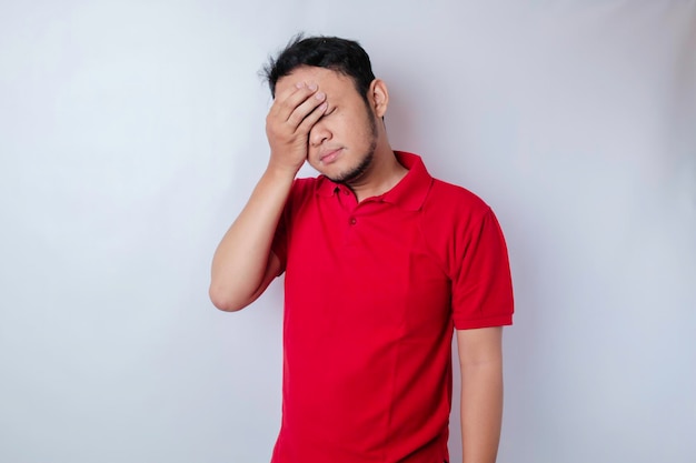 A portrait of an Asian man wearing a red tshirt isolated by white background looks depressed