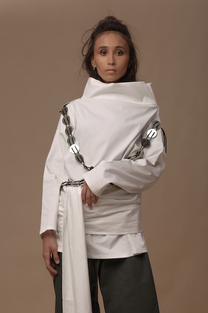 Portrait of asian model in a white cotton blouse with harness and khaki trousers