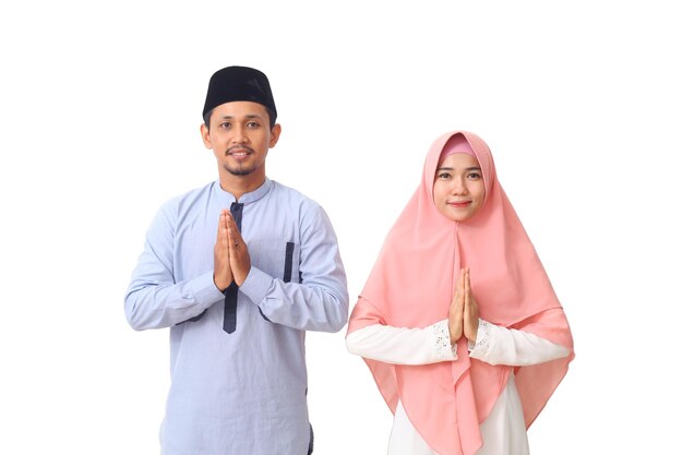 Portrait of asian muslim couple are doing a greeting pose as a symbol of forgiveness. asian muslims are celebrating eid mubarak. woman's hand in her chest. isolated on white background