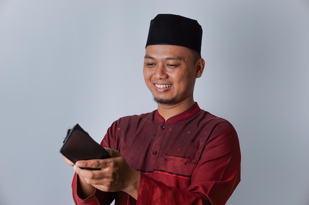 Portrait of an Asian Muslim man smiling at the contents of his wallet