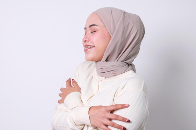 Portrait of Asian muslim woman embracing herself and smiling with pleasure feeling self pride