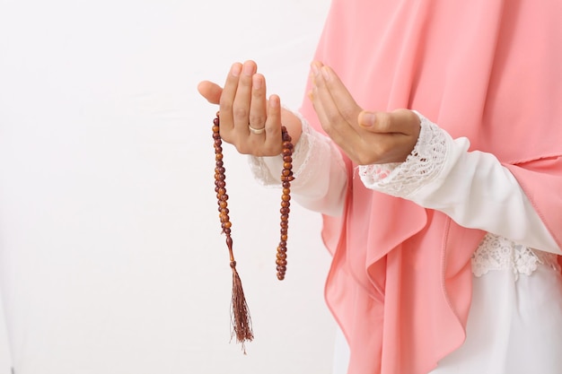 A portrait of asian muslim woman wearing a veil or hijab\
praying with prayer beads on her hand. close up shoot. isolated on\
white background with copy space