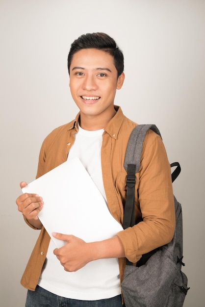 Portrait of Asian teenage college boy holding books and documents against white background