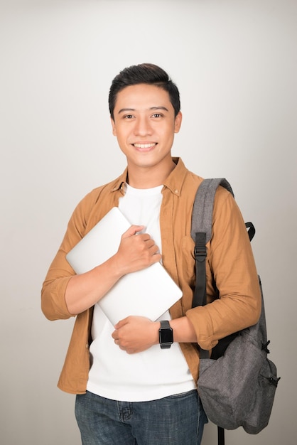 Portrait of Asian teenage college boy holding books and documents against white background