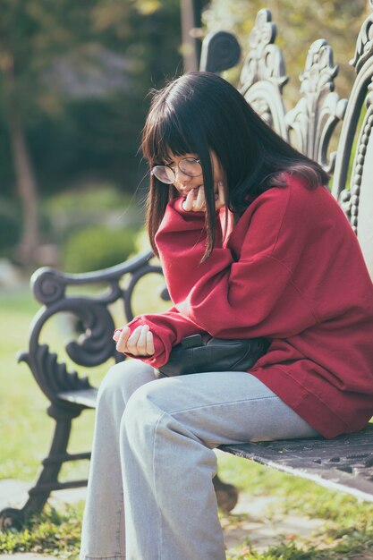 Portrait of asian teenager wearing eyeglasses sitting on bench