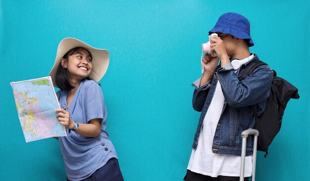 portrait of Asian tourist man taking picture of his girlfriend in blue background