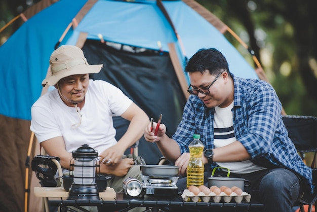 Portrait of Asian traveler men cooking at campsite Outdoor cooking traveling camping lifestyle concept