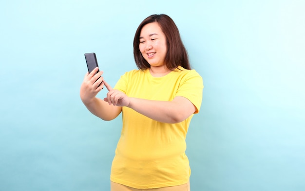 Portrait of Asian woman being Shock and surprised after reading message from smartphone, isolated   in studio.