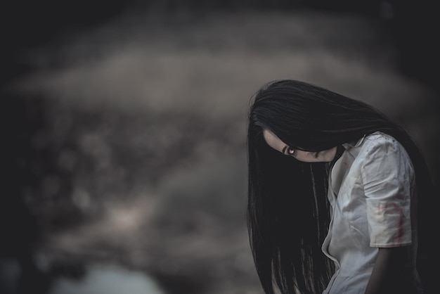 Portrait of asian woman make up ghost face at the swamHorror sceneScary background