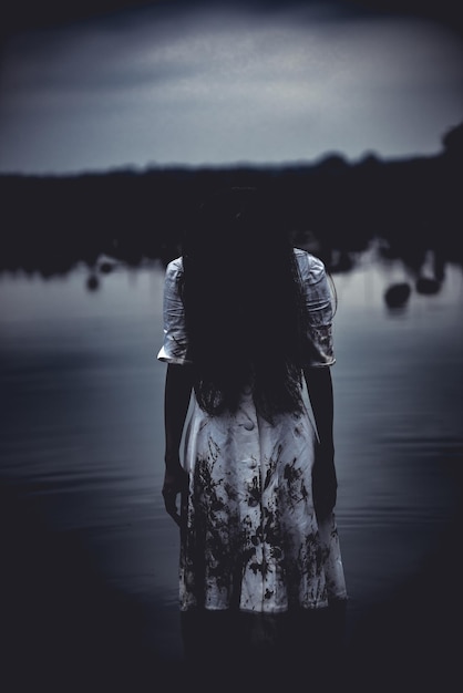 Photo portrait of asian woman make up ghost face at the swamphorror scenescary backgroundhalloween postert