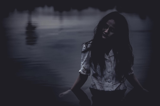アジアの女性の肖像画は、沼地で幽霊の顔を作りますホラーシーン怖い背景ハロウィーンのポスターT