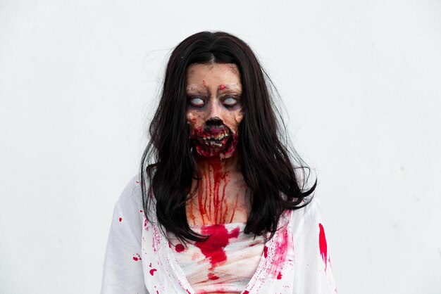 Portrait of asian woman make up ghost face with blood on white backgroundHorror sceneScary backgroundHalloween posterThailand people