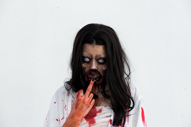 Portrait of asian woman make up ghost face with blood on white backgroundHorror sceneScary backgroundHalloween posterThailand people