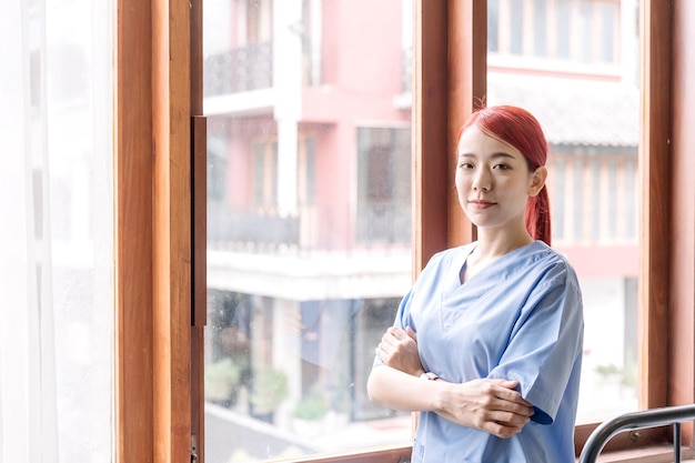 환자 간병인이 집에 방문하는 집에서 의료 수술복을 입은 아시아 여성 간호사의 초상화