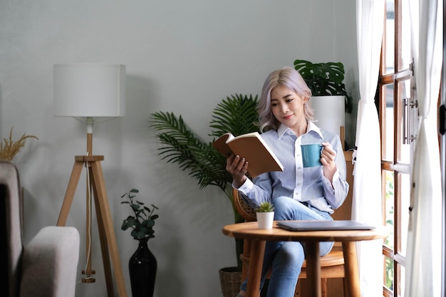 Portrait Asian woman reading book and relaxing with coffee at home