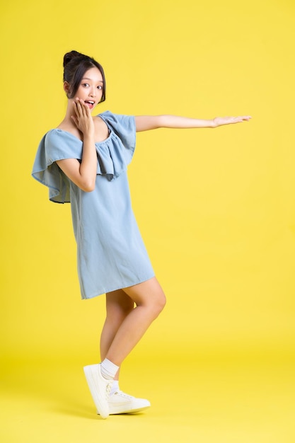 Portrait of Asian woman in skirt posing on yellow background