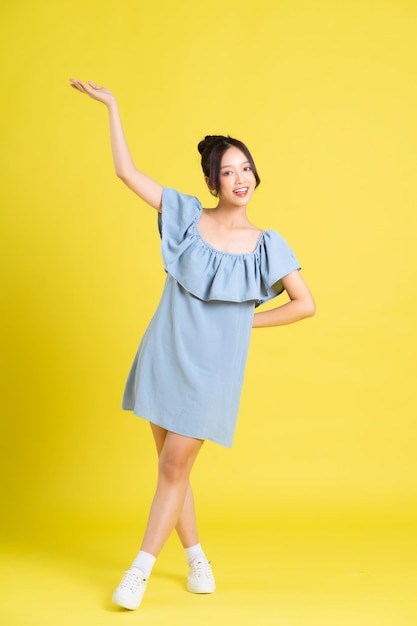 Portrait of Asian woman in skirt posing on yellow background