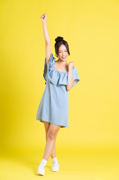 Portrait of Asian woman in skirt posing on yellow background