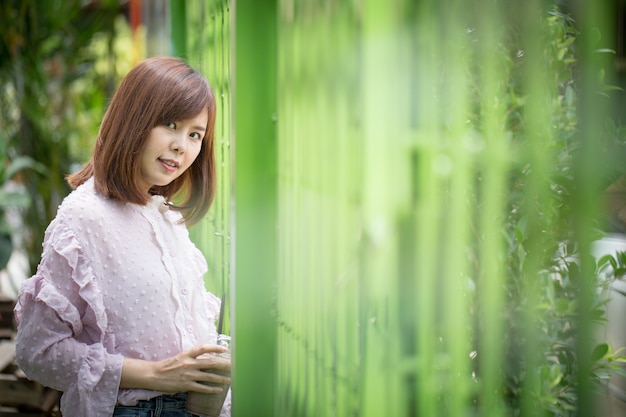 Foto donna asiatica del ritratto che sorride nel giardino della caffetteria