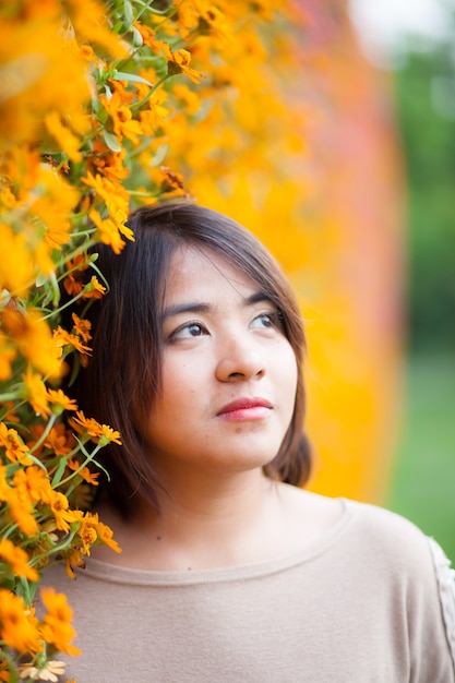 Portrait Asian woman standing near yellow flowers.