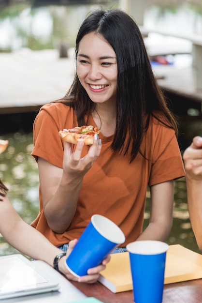 야외 대학, 교육 개념에서 맛있는 치즈와 함께 피자를 먹는 세로 아시아 여자 학생들