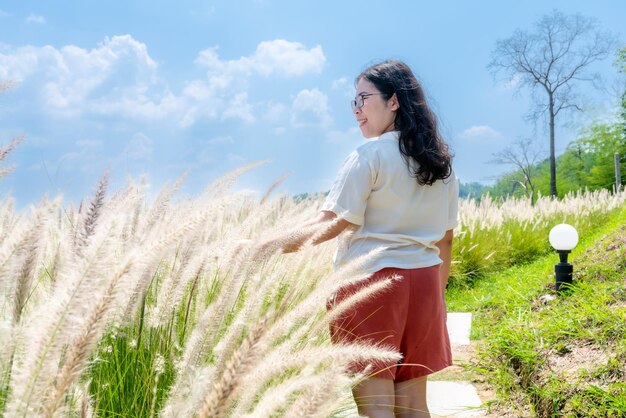 Portrait asian woman tourist in white dress and white grass of flowering crimson fountaingrass view mountain range on nature trail in khao kho national park in phetchabunthailand blue sky