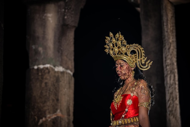 Il ritratto della donna asiatica indossa lo stile tailandese antico dell'abito e la faccia del fantasma del trucco ai vecchi castelli alla scena di notte la gente della tailandia