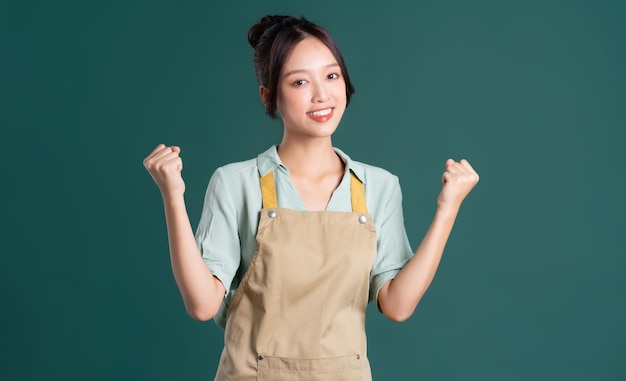 Portrait of Asian woman wearing apron on green background