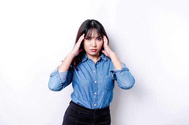 A portrait of an Asian woman wearing a blue shirt isolated by white background looks depressed