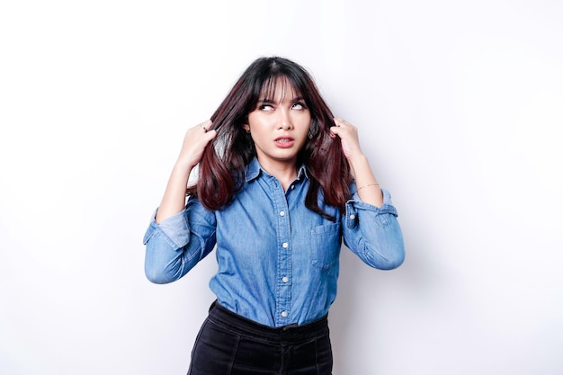 A portrait of an Asian woman wearing a blue shirt isolated by white background looks depressed