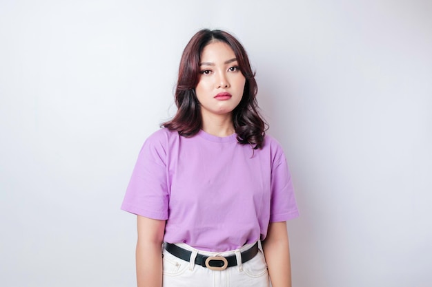 A portrait of an Asian woman wearing a lilac purple tshirt isolated by white background looks depressed