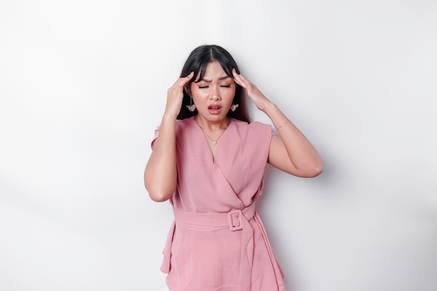 Портрет азиатки в розовой блузке на белом фоне выглядит подавленным
