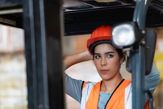 Photo portrait of an asian woman with a forklift used to lift heavy objects in a warehouse