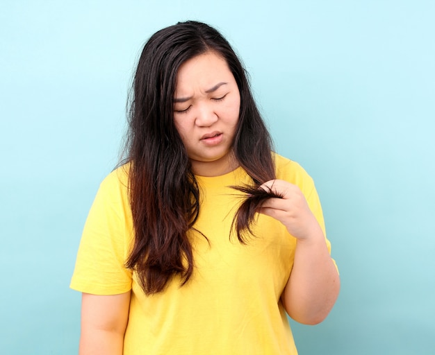 Portrait asian woman with hair problems - brittle, damaged, dry, dirty and loss hair,on blue background in studio.