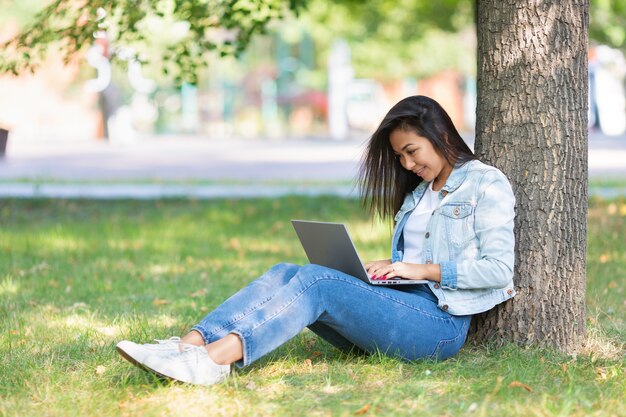 Portrait of an asian woman with laptop in city park during online working or distant online education