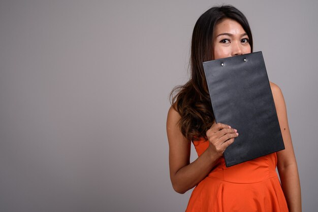 Portrait of Asian woman with wavy hair holding clipboard