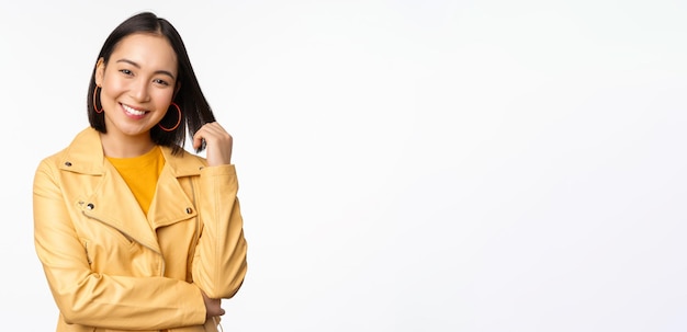 Portrait of asian woman in yellow jacket smiling and looking happy standing over white background Copy space