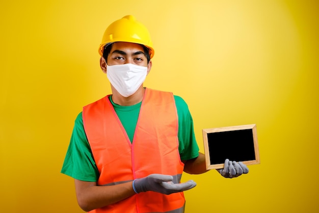 Portrait of asian workman wearing protective mask against the coronavirus holding small blackboard