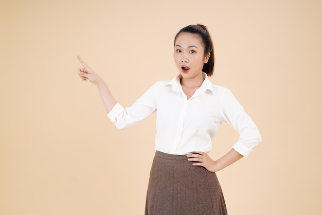 Portrait of Asian young beautiful and cheerful woman point finger with hand gesture isolated on background