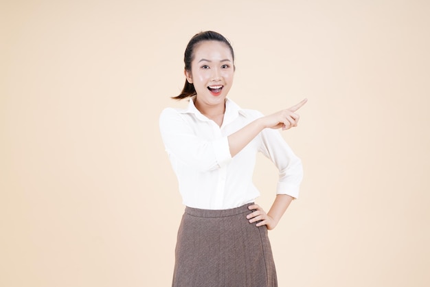 Portrait of Asian young beautiful and cheerful woman point finger with hand gesture isolated on background