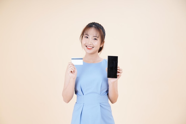 Portrait of Asian young beautiful and cheerful woman using credit card to pay online isolated on background