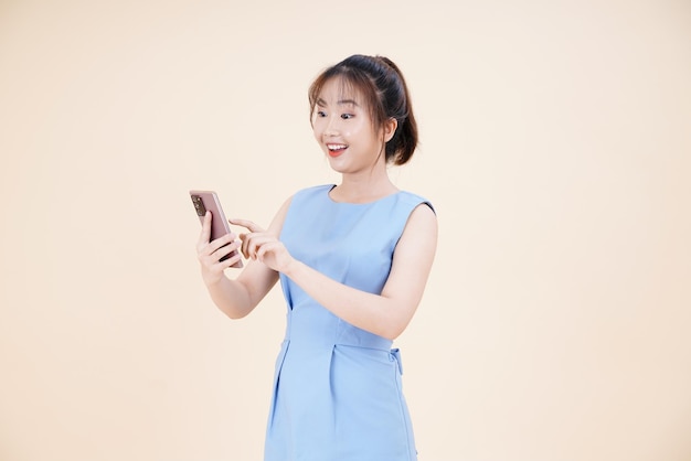 Portrait of Asian young beautiful and cheerful woman using smart phone isolated on background