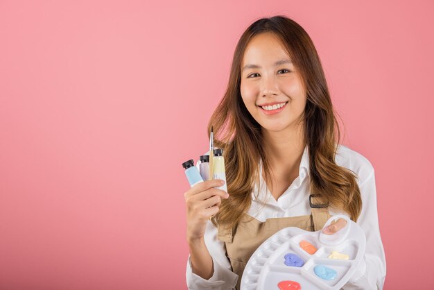 Portrait asian young woman artist holding brush and paint palette happy female painting using person