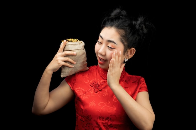 Portrait Asian young woman red dress traditional cheongsam holding a gold coin in a sack