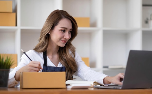 Ritratto di giovane donna asiatica pmi che lavora con una scatola a casa il posto di lavorostartup piccolo imprenditore piccolo imprenditore pmi o attività freelance online e concetto di consegna