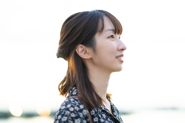 Portrait of asian young woman standing by the sea in evening