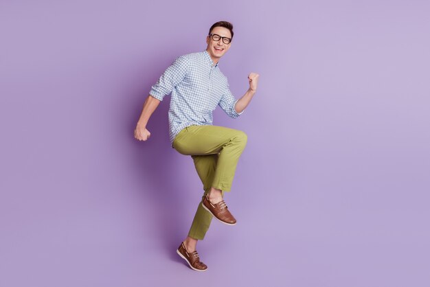 Portrait of astonished excited guy celebrate victory raise fists on purple background