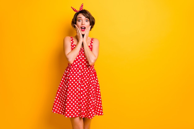 Portrait of astonished girl hear unbelievable unexpected novelty impressed touch hands face scream wear polka-dot skirt isolated over vivid color wall